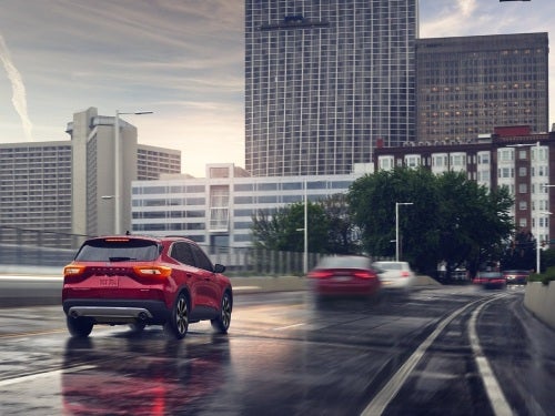 2024 Ford Escape Plug-in Hybrid driving into a city on a wet road