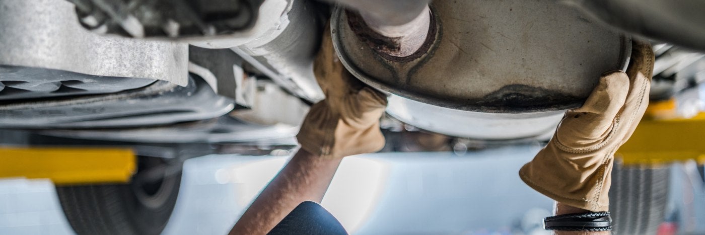 Close up view of a service tech checking out a vehicle's catalytic converter